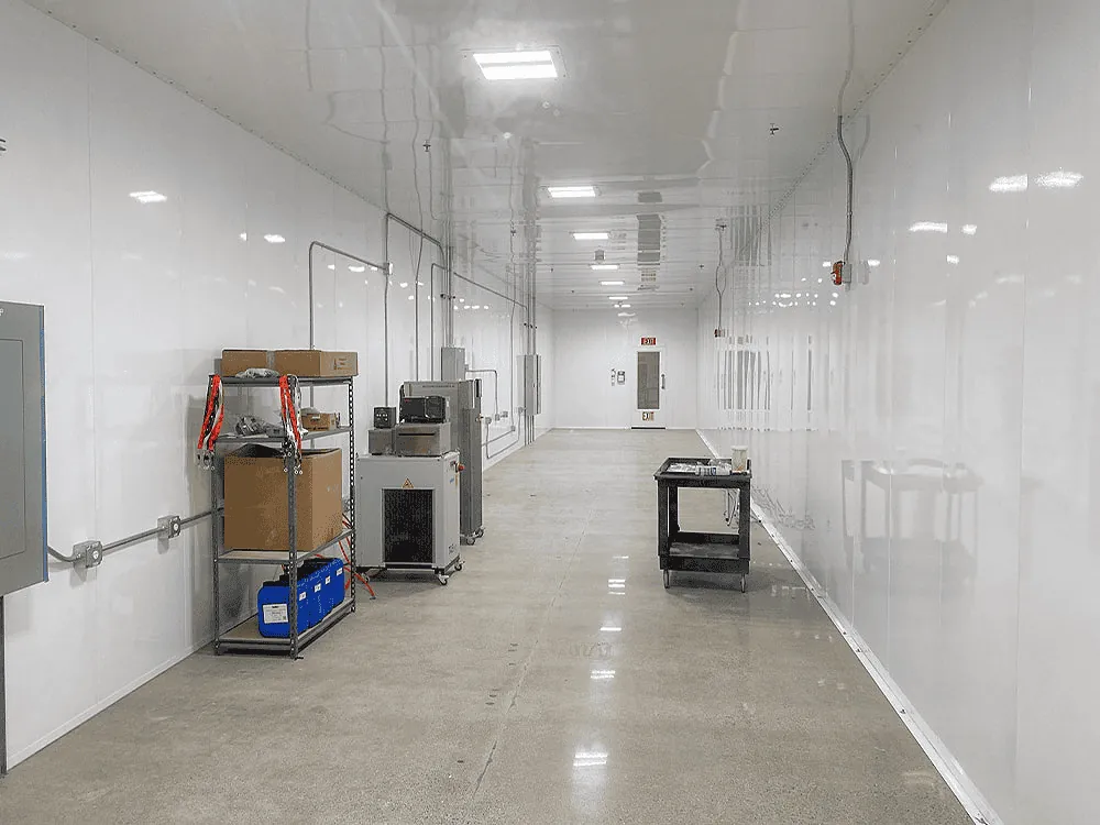 Production-floor view with strip-curtain pass-through, equipment staging, and high-bay LED illumination throughout.