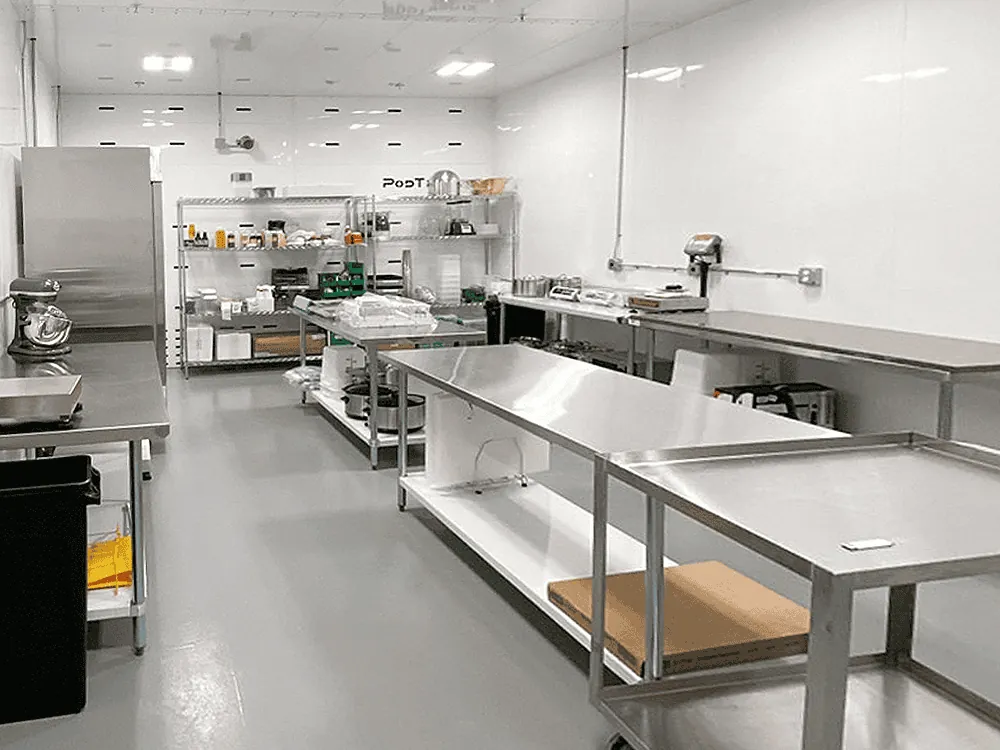 Adjacent post-processing room outfitted with stainless steel work tables, scales, mixers, and shelving for downstream operations and packaging.